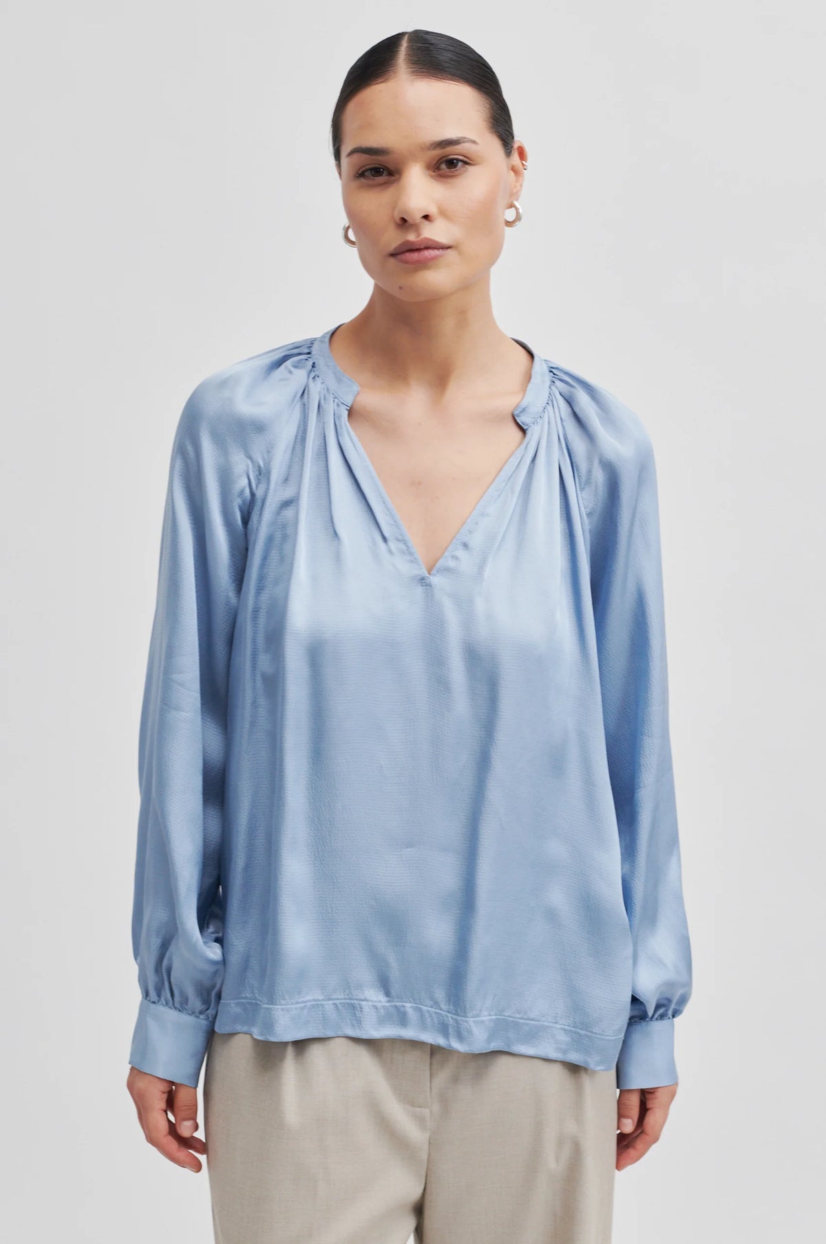 Long sleeved blue textured fabric notch neck top with raglan sleeves and gathered neckline
