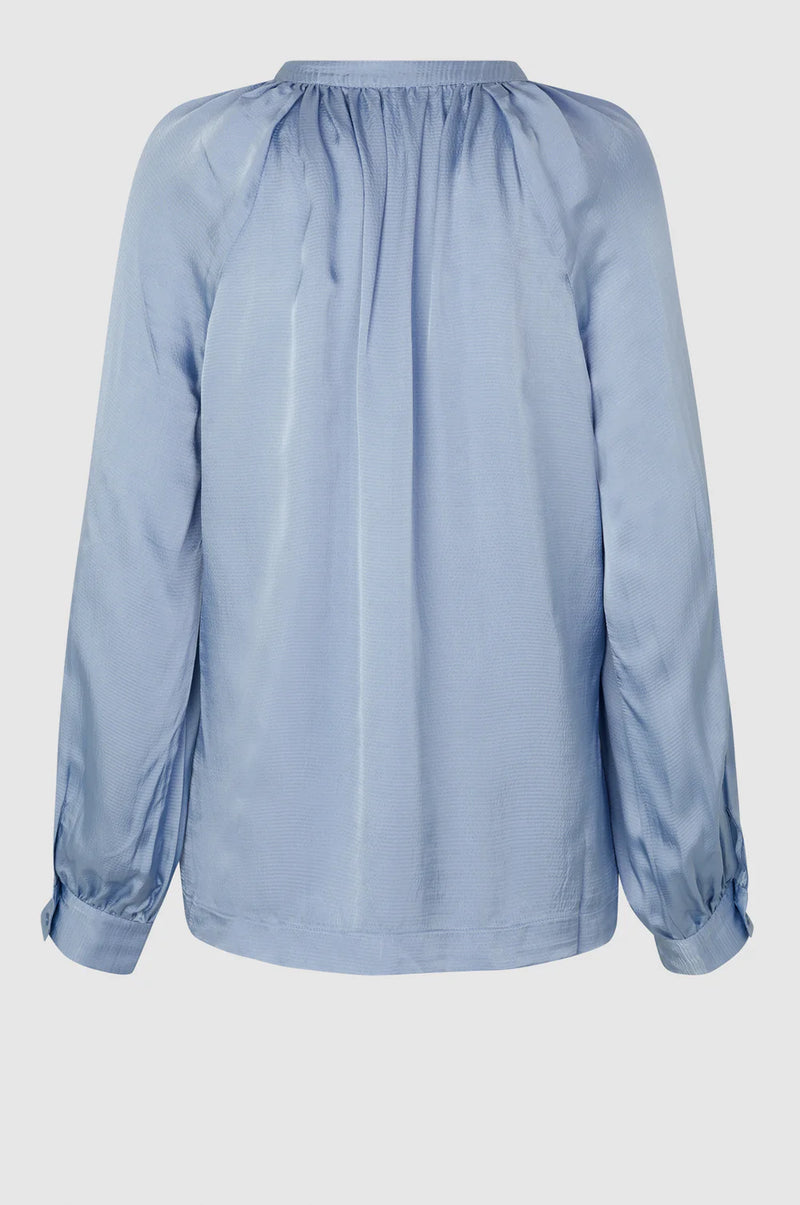 Long sleeved blue textured fabric notch neck top with raglan sleeves and gathered neckline