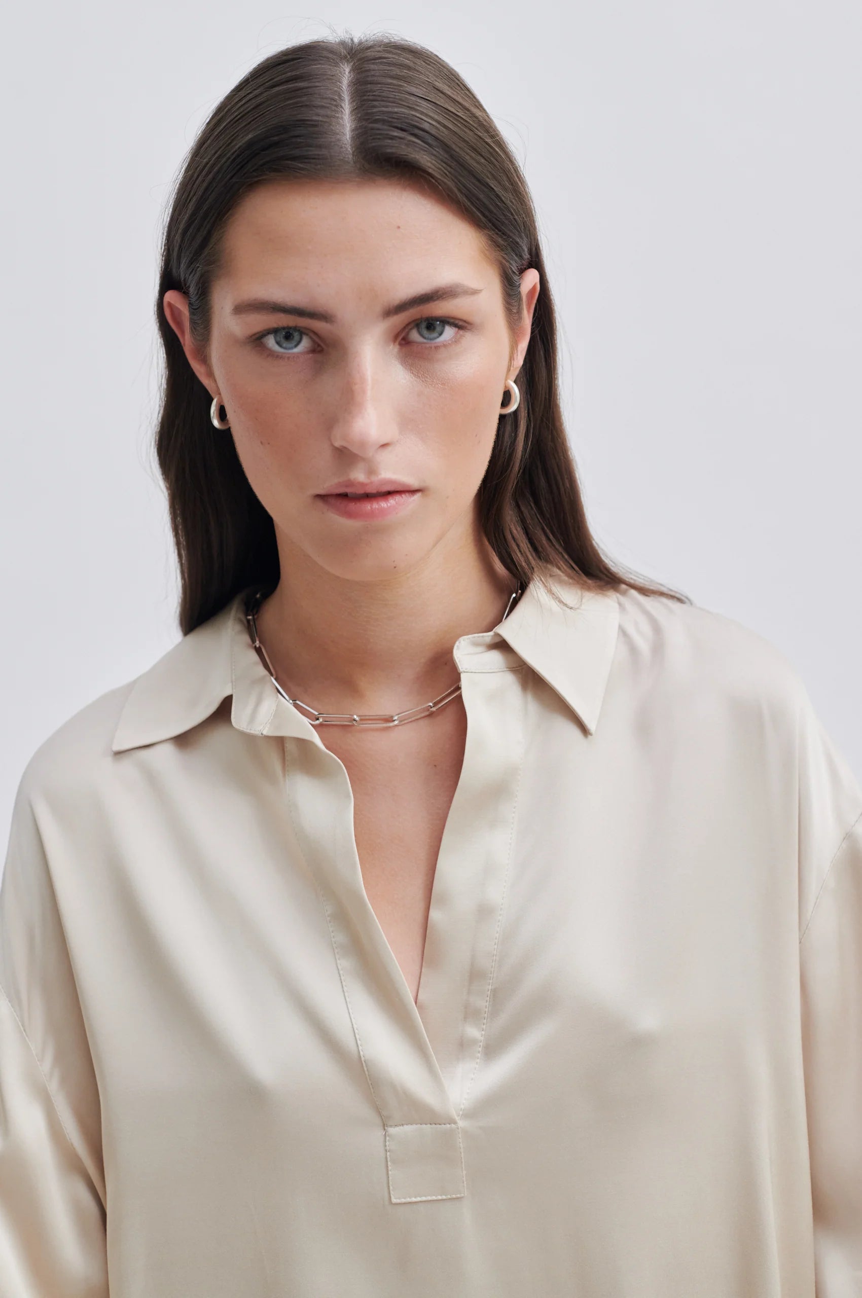 Satin ivory notch neck pull on top with long sleeves and a classic collar