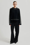 black round neck jumper with contrasting white stripes, long sleeves and ribbing model shot 