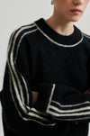 black round neck jumper with contrasting white stripes, long sleeves and ribbing close up