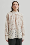 floral lace blouse on sheer background with high neck and buttoned cuffs 