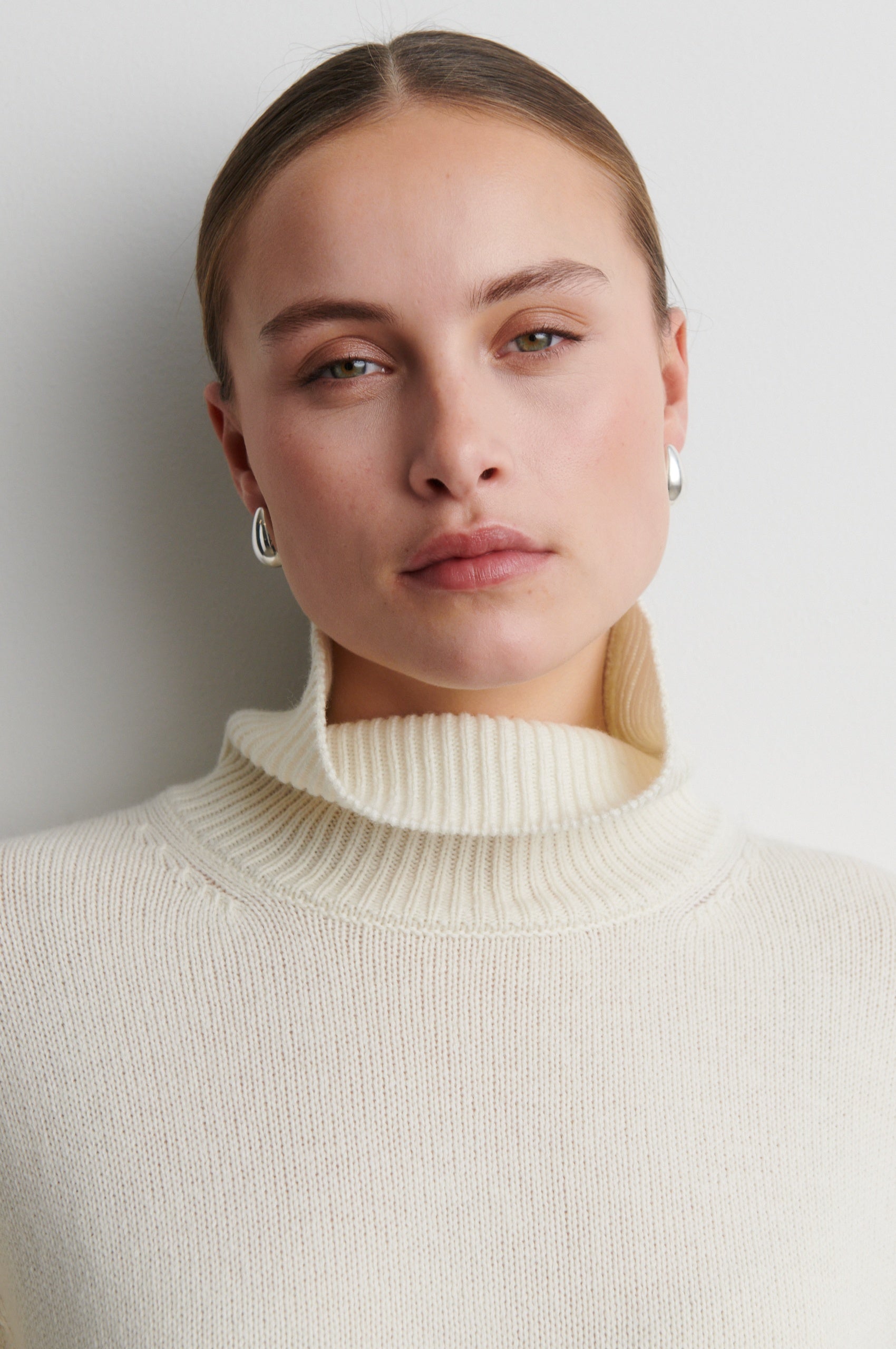 Woman wearing a cream turtleneck sweater against a plain background from Second Female