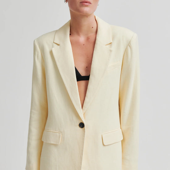 Woman wearing a light yellow suit with a plain background