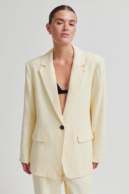 Woman wearing a light yellow suit with a plain background