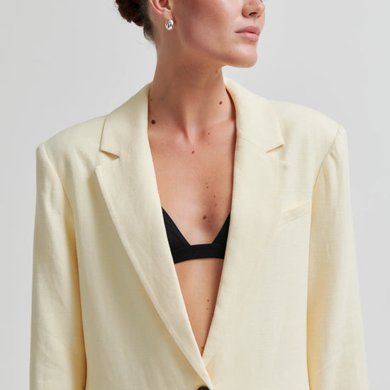 Woman wearing a light yellow blazer over a black top against a plain background from Second Female