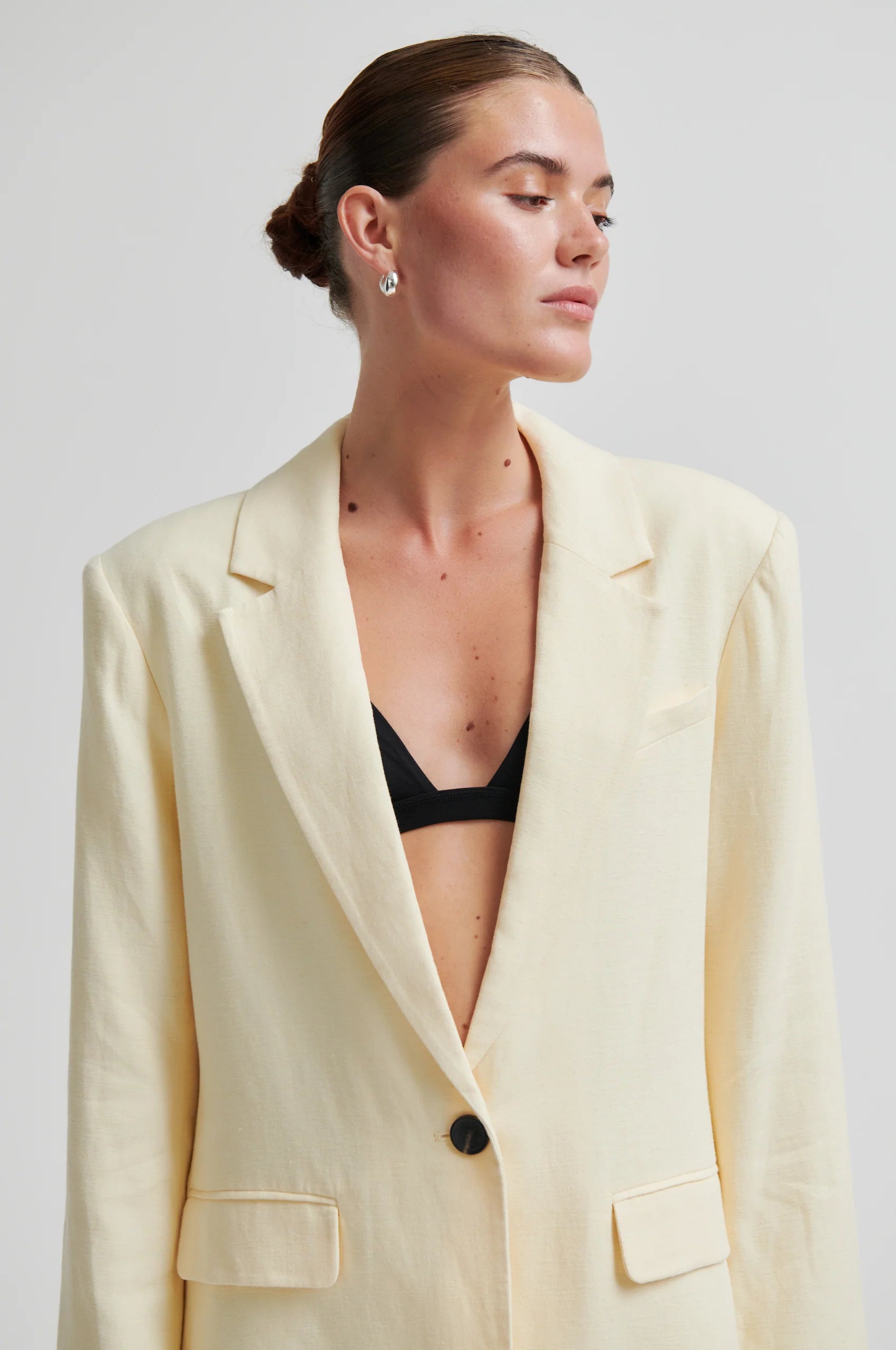 Woman wearing a light yellow blazer over a black top against a plain background from Second Female