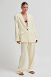 Woman wearing a light yellow suit on a white background from Second Female