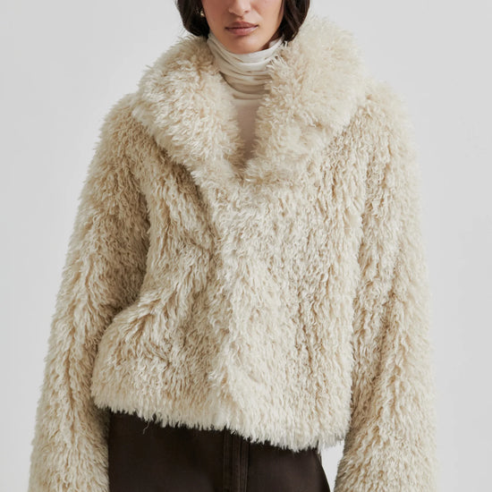 Person wearing a fluffy beige jacket on a white background
