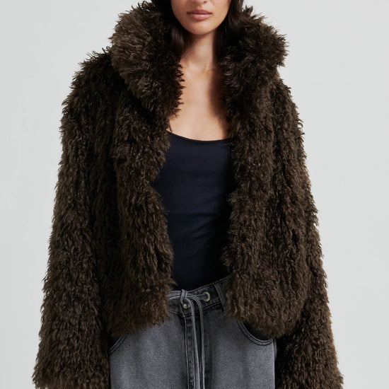 Woman wearing a brown fluffy jacket on a plain background