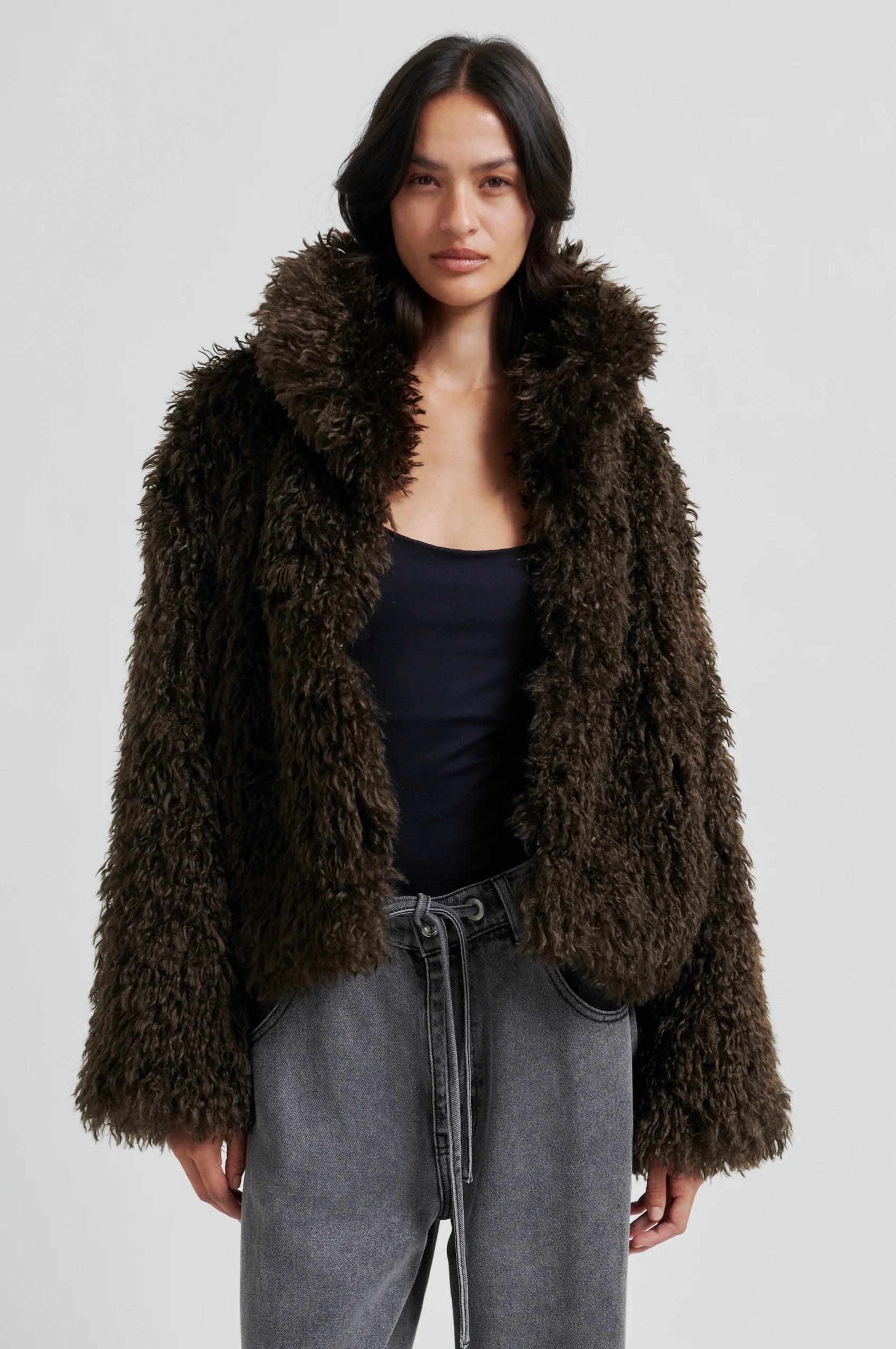 Woman wearing a brown fluffy jacket on a plain background