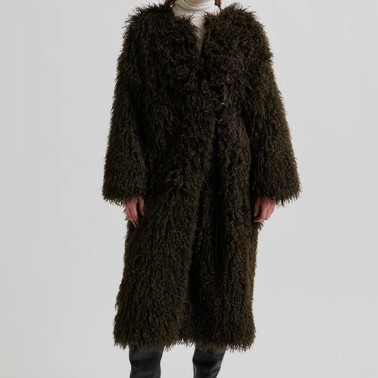 Woman wearing a long brown fur coat on a white background