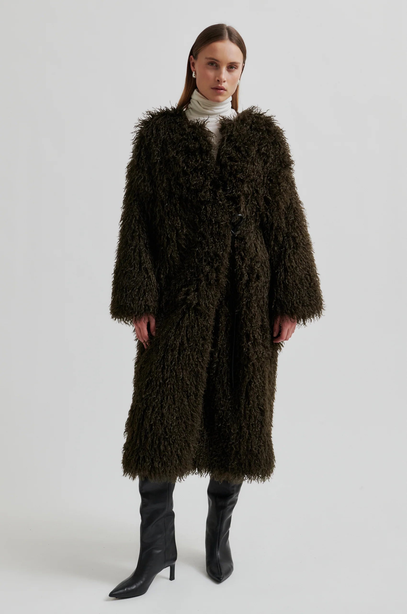 Woman wearing a long brown fur coat on a white background