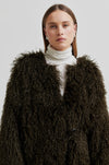 Woman wearing a brown fluffy coat against a plain background