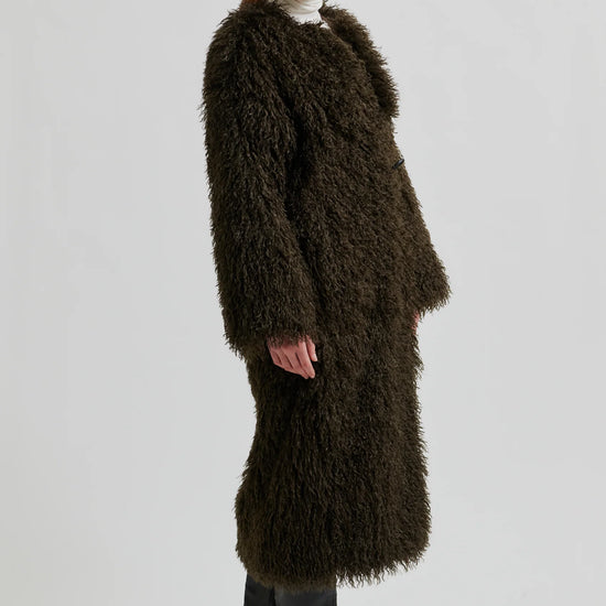 Woman wearing a long brown fur coat on a white background