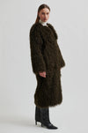Woman wearing a long brown fur coat on a white background