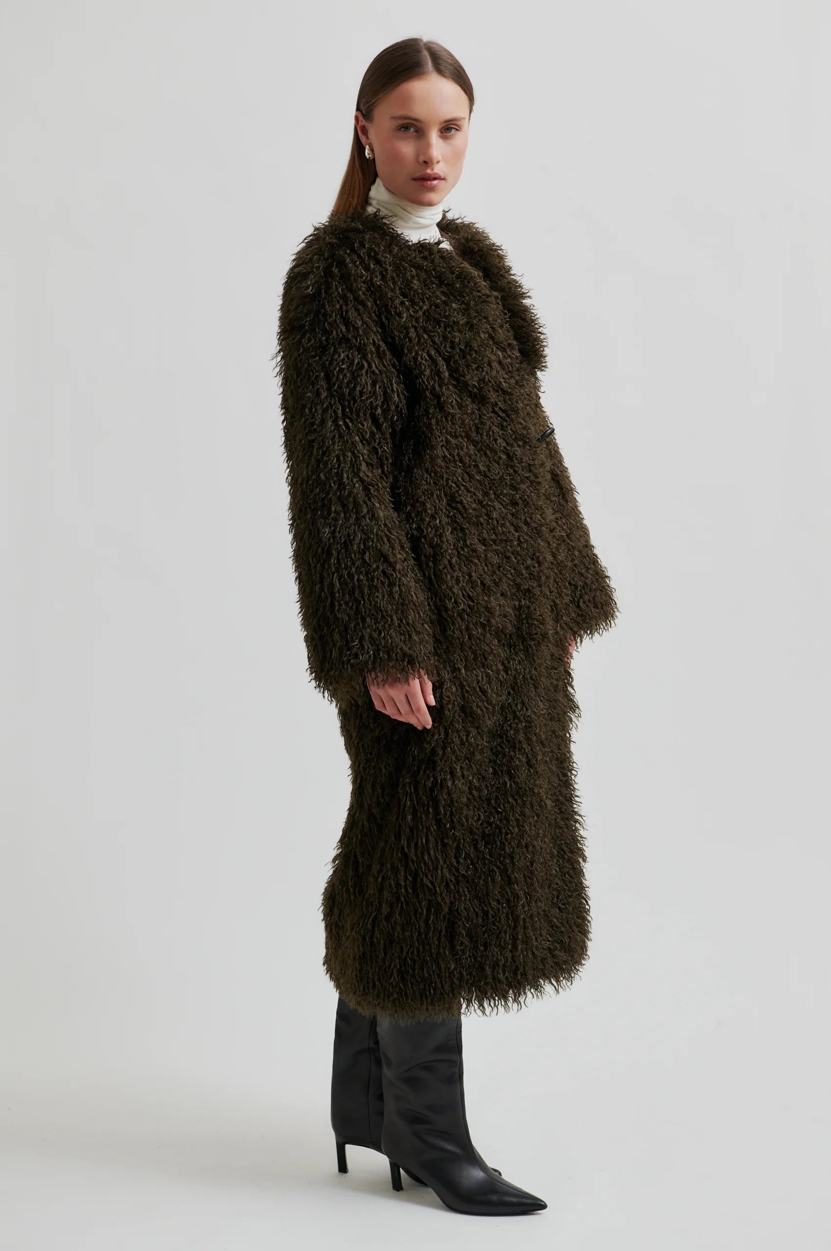Woman wearing a long brown fur coat on a white background