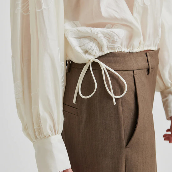 round neck ecru blouse with tonal floral print with long cuffed sleeves close up of hem