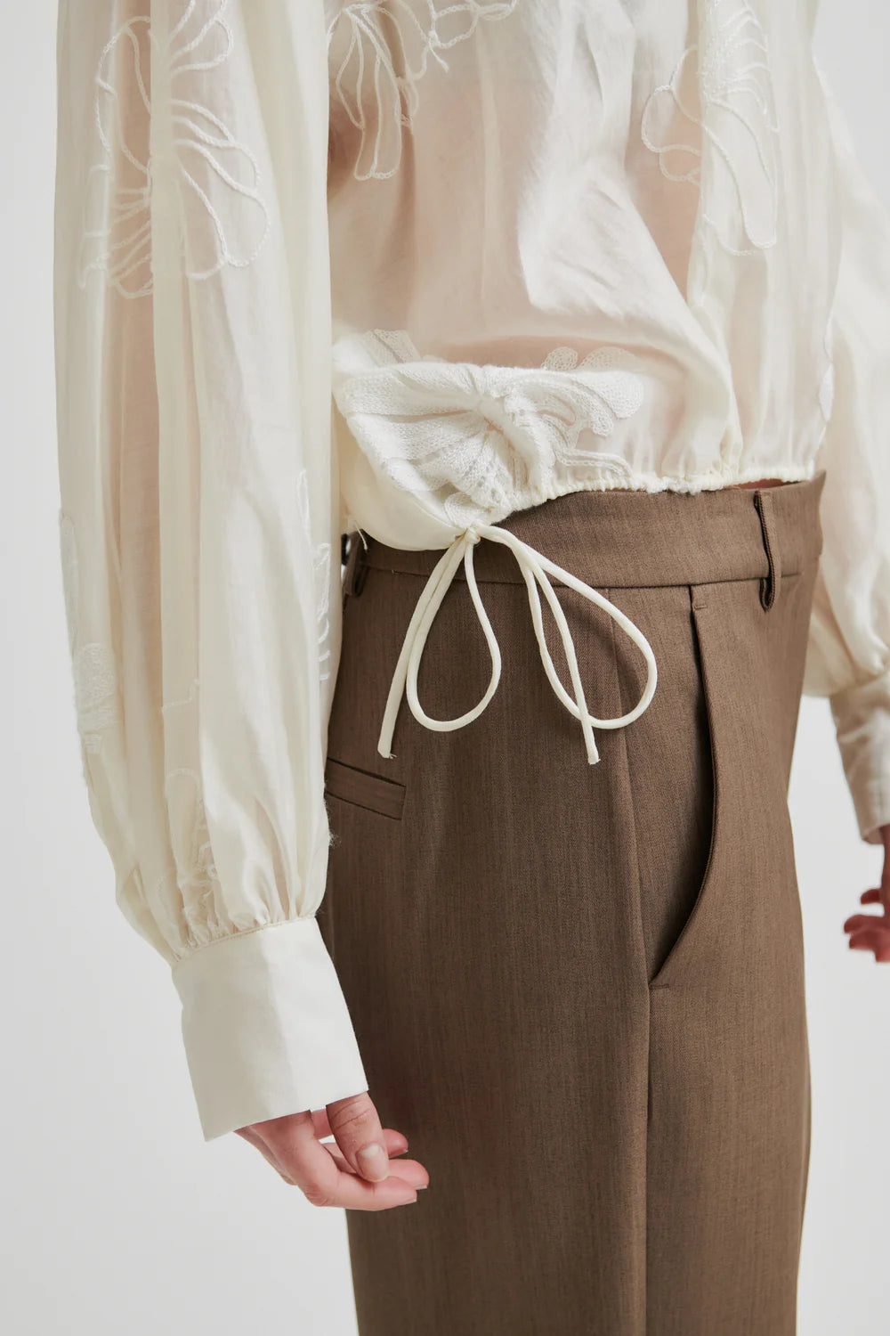 round neck ecru blouse with tonal floral print with long cuffed sleeves close up of hem