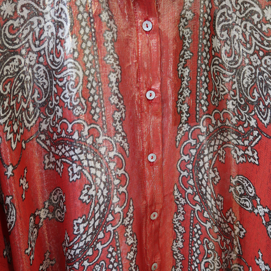 Close-up of a red shirt with intricate white, gold and black paisley patterns