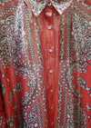 Close-up of a red shirt with intricate white, gold and black paisley patterns
