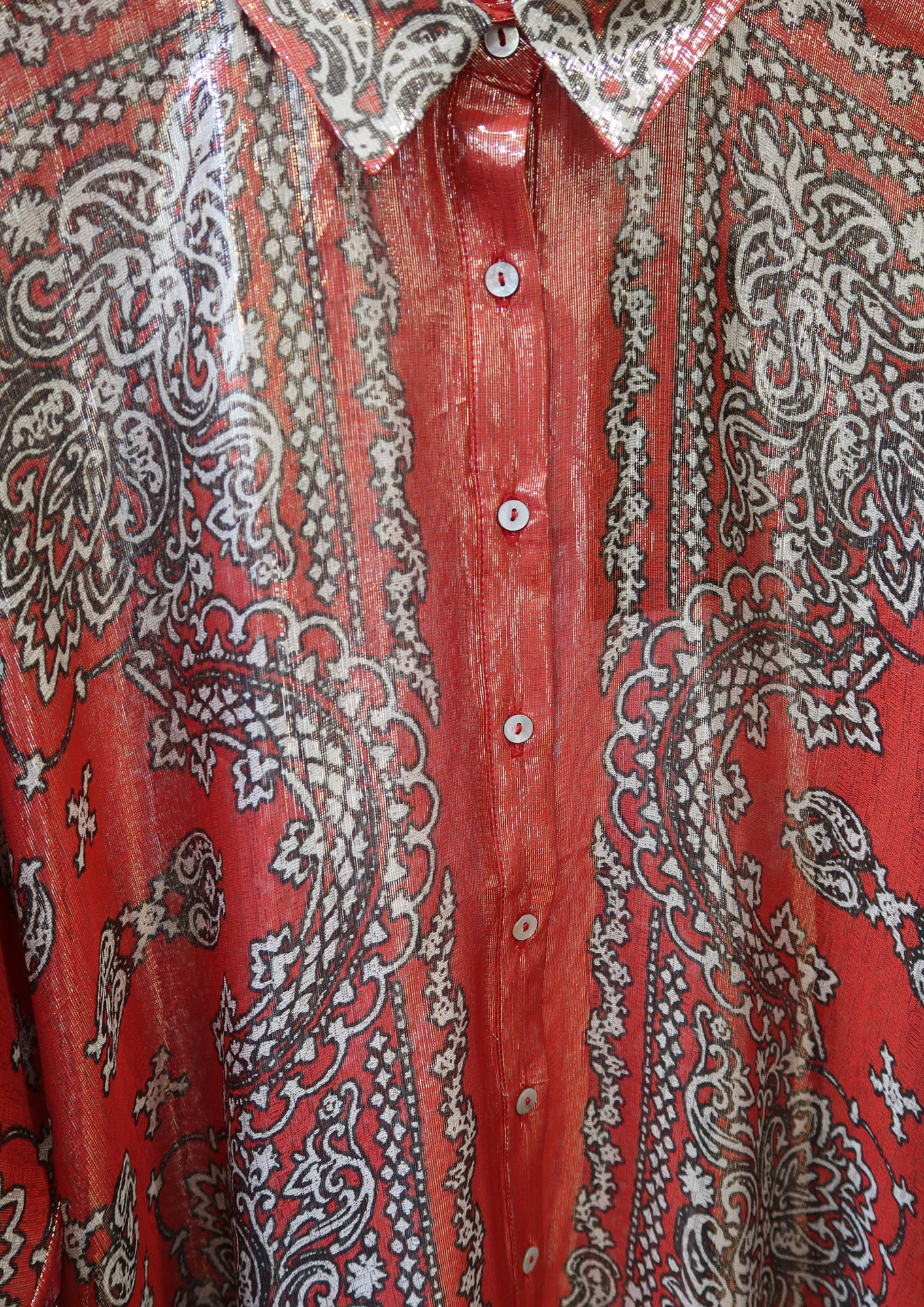 Close-up of a red shirt with intricate white, gold and black paisley patterns