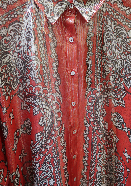 Close-up of a red shirt with intricate white, gold and black paisley patterns