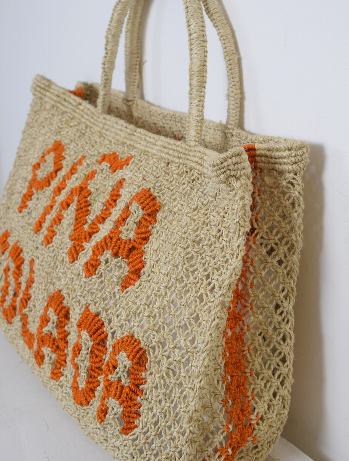 Woven nautral bag with pina colada writen on it in orange