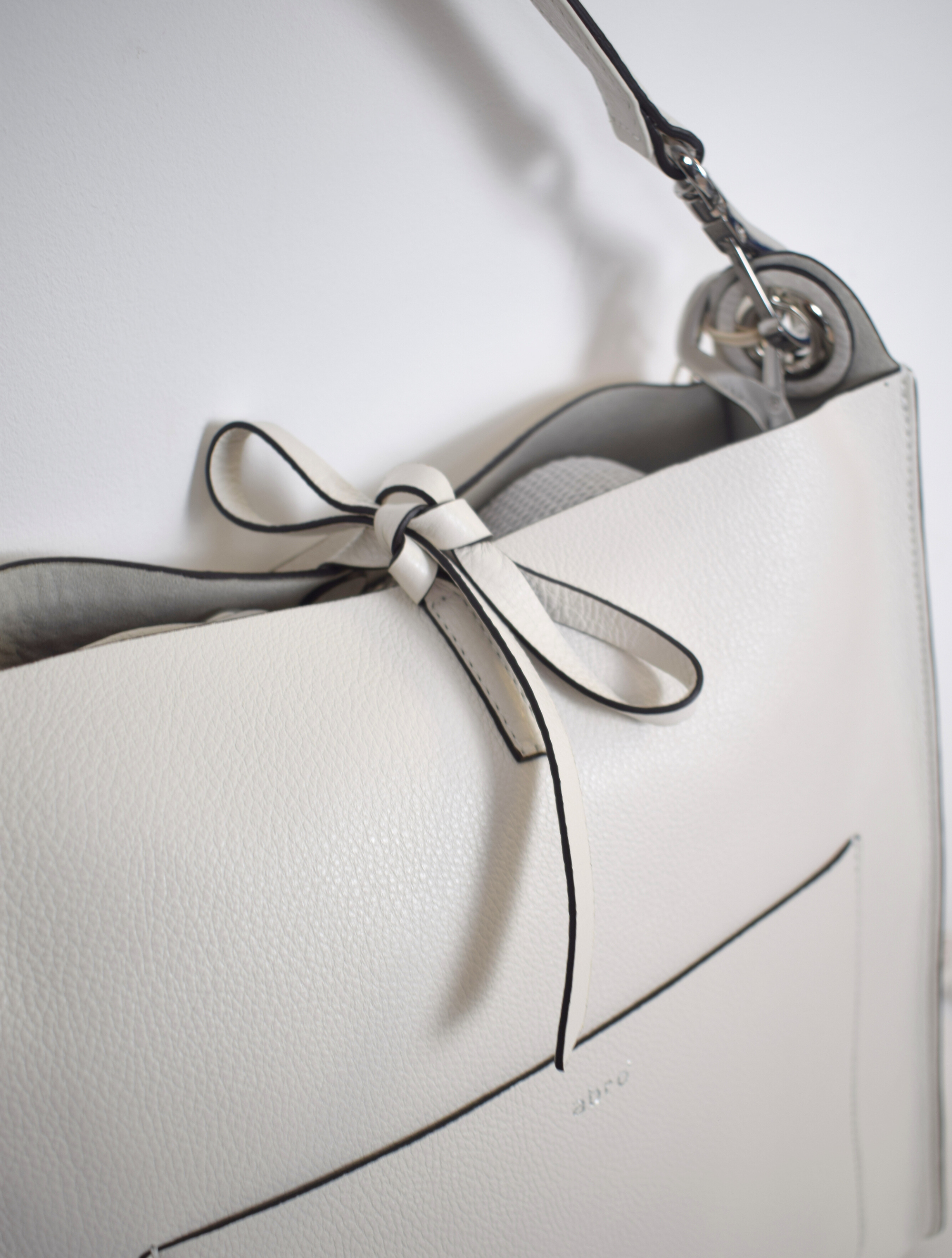 ivory leather bag with silver hardware.  A cross body strap and a handle. 