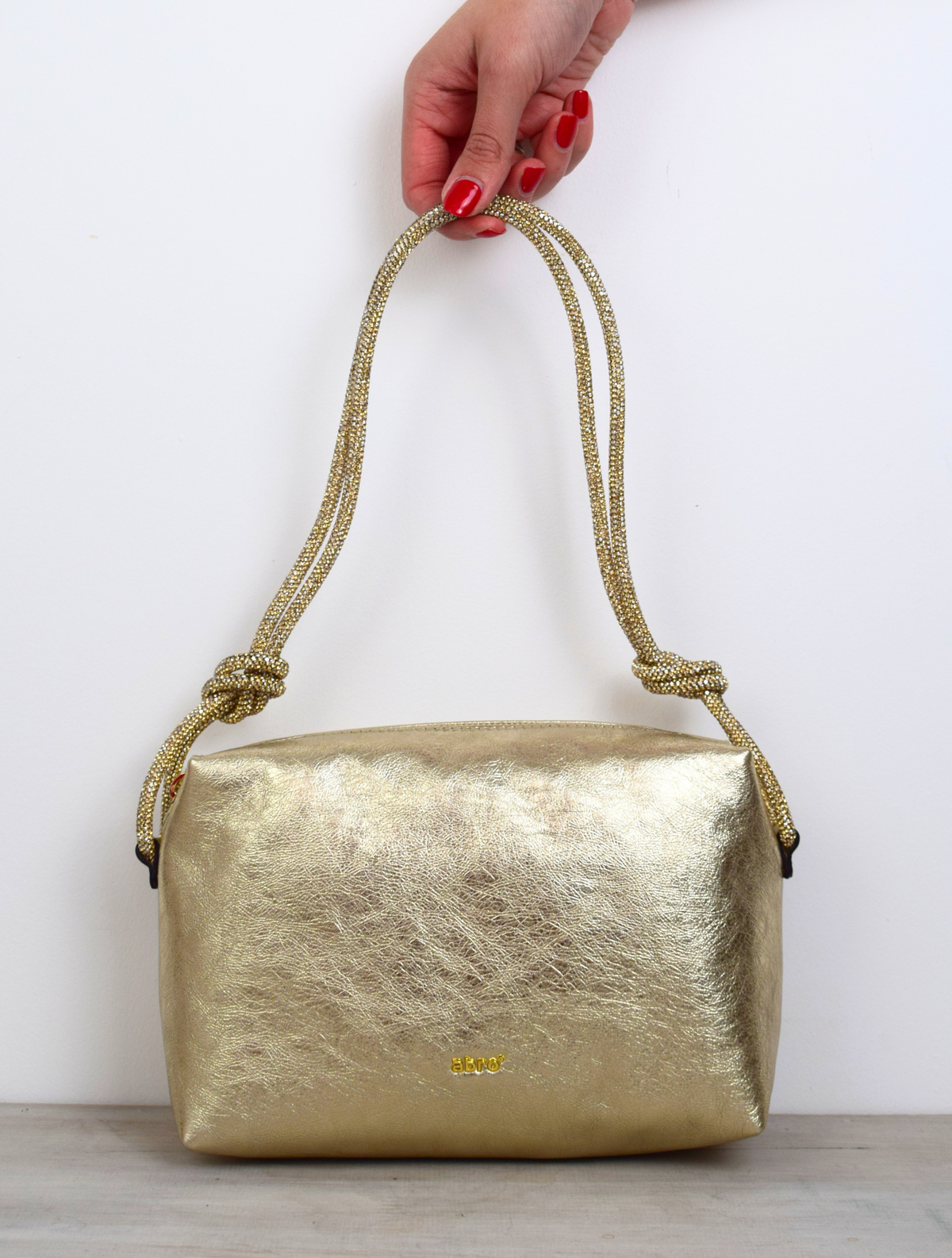 rectangular gold coloured leather bag with sparkly knotted shoulder strap
