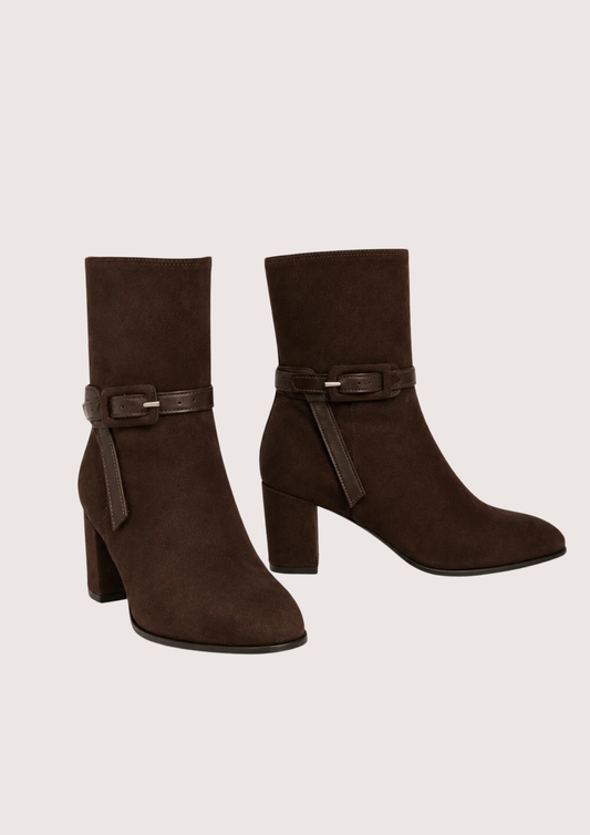 A pair of dark brown suede ankle boots with block heels and a matching faux-leather buckle strap around the ankle, shown against a plain light beige background.