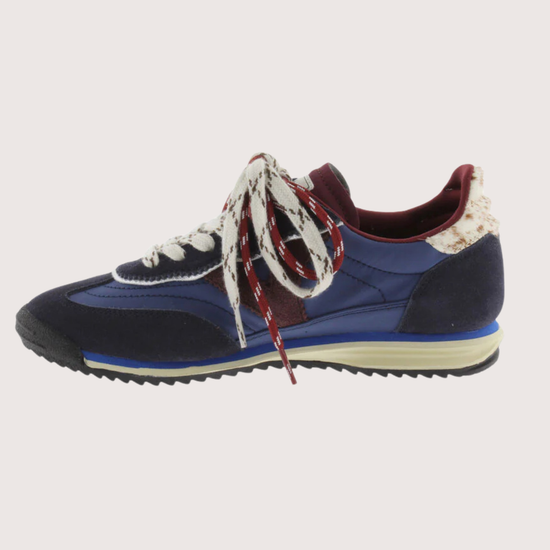 A low-top fashion sneaker, featuring navy blue suede and mesh panels, burgundy accents, patterned white and burgundy laces, and a cream midsole, shown against a plain light gray background.