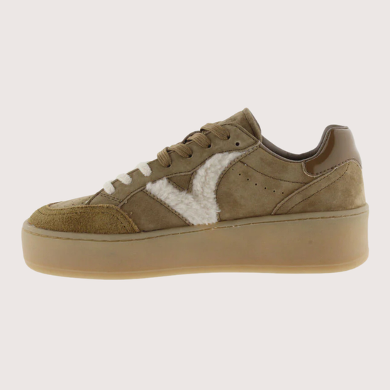 A low-top platform sneaker in taupe brown suede and leather, featuring a contrasting white faux-fur panel on the side and a thick tan sole.