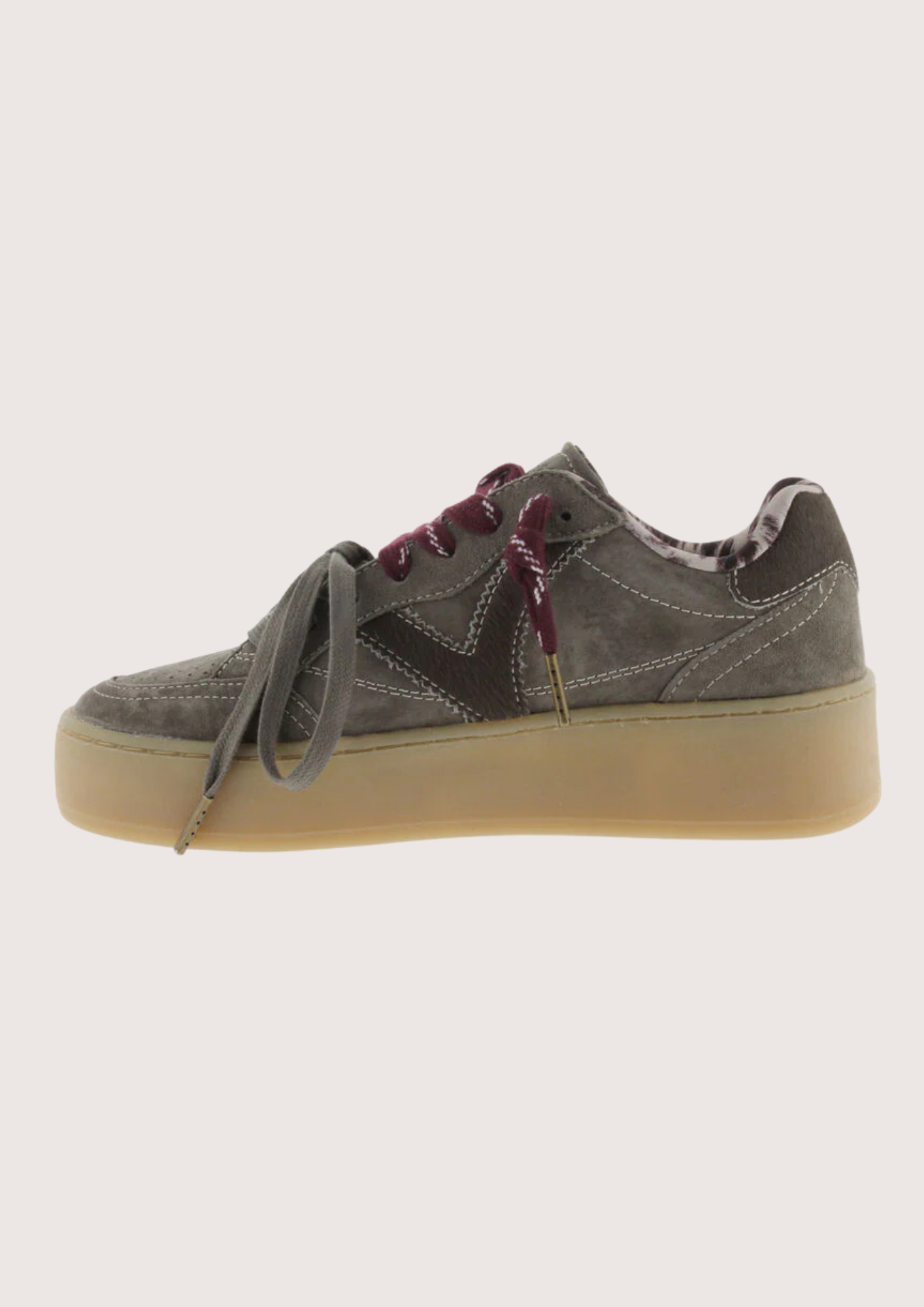 A low-top platform sneaker in dark gray suede and leather, featuring a thick beige gum sole, gray laces, and burgundy ribbon laces tied in a bow.