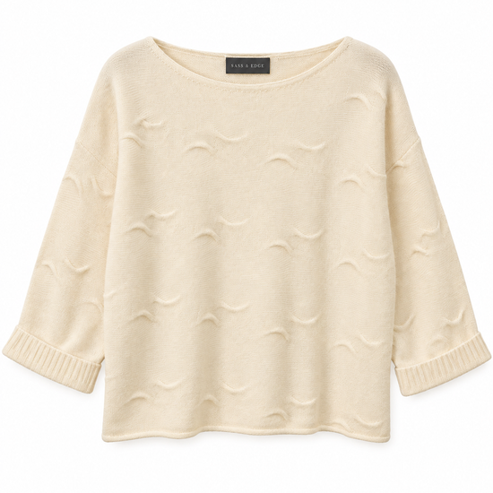 Flat lay image of a white cashmere knit, with wave detailing in the stitching and shorter length sleeves