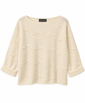 Flat lay image of a white cashmere knit, with wave detailing in the stitching and shorter length sleeves
