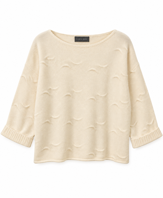 Flat lay image of a white cashmere knit, with wave detailing in the stitching and shorter length sleeves