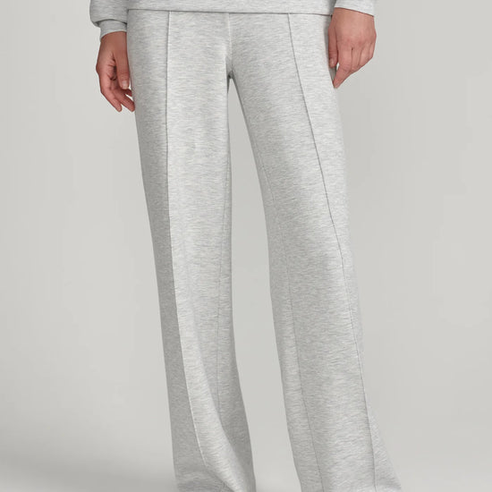 A person wearing light heather gray wide-leg sweatpants with a matching sweatshirt partially visible, standing against a plain light gray studio background.