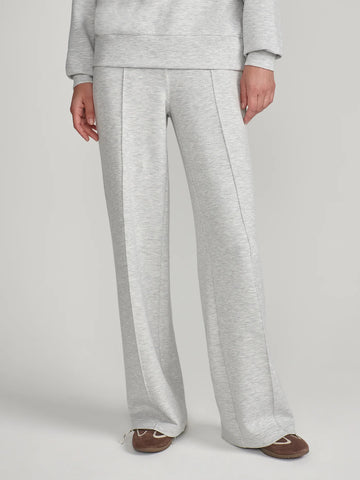 A person wearing light heather gray wide-leg sweatpants with a matching sweatshirt partially visible, standing against a plain light gray studio background.