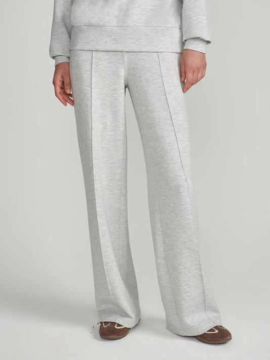 A person wearing light heather gray wide-leg sweatpants with a matching sweatshirt partially visible, standing against a plain light gray studio background.