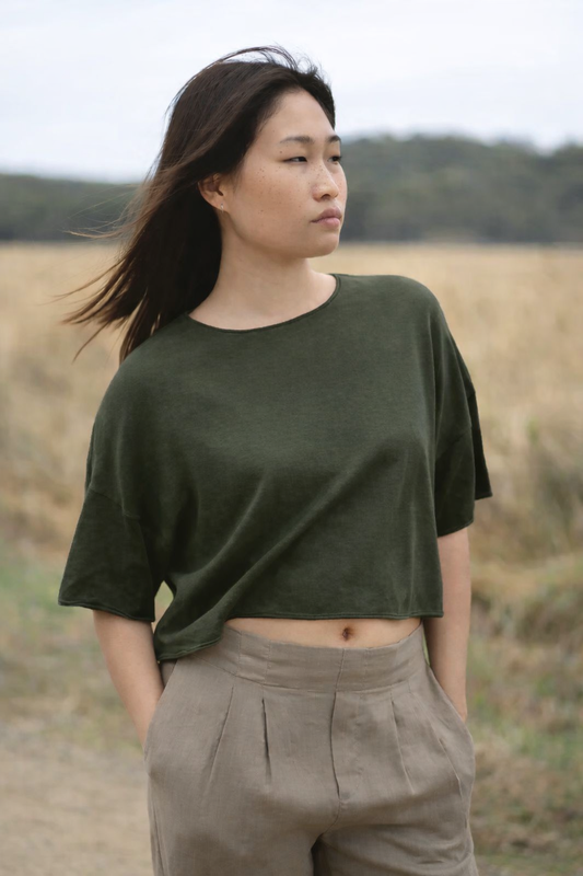 Woman wearing an olive green cotton cashmere top and beige pants from Lilly Pilly