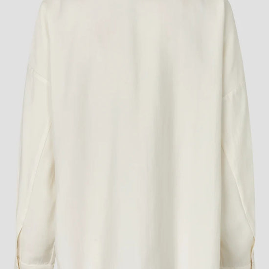 An off-white long-sleeve shirt shown from the back, featuring a relaxed fit and a subtle textured fabric, set against a solid light gray background.