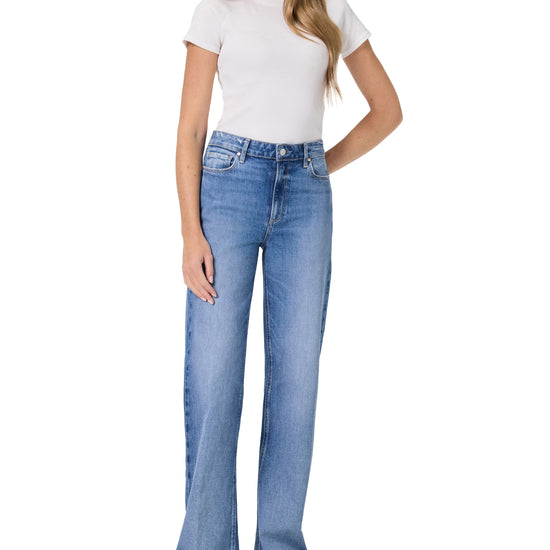 Woman wearing blue flared jeans and a white t-shirt on a white background