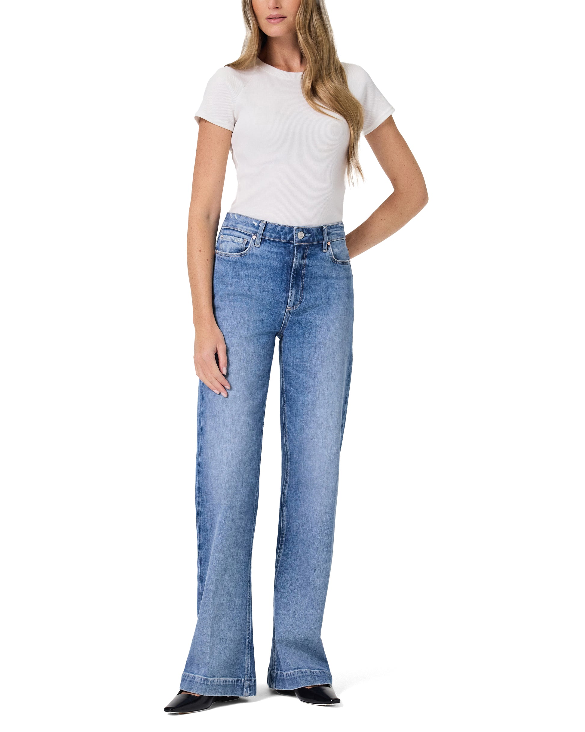 Woman wearing blue flared jeans and a white t-shirt on a white background