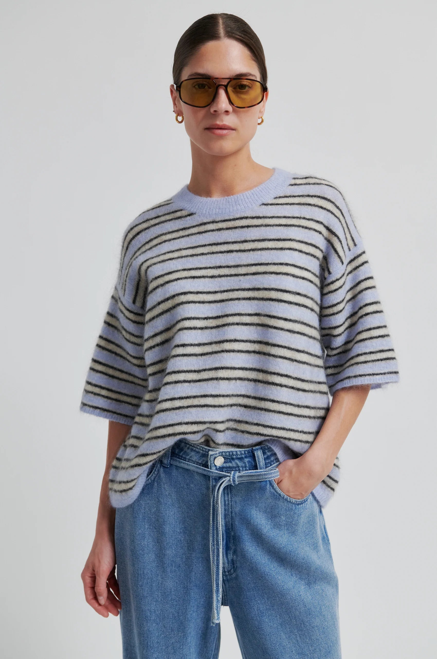 Person wearing a striped sweater and sunglasses against a plain background from Second Female