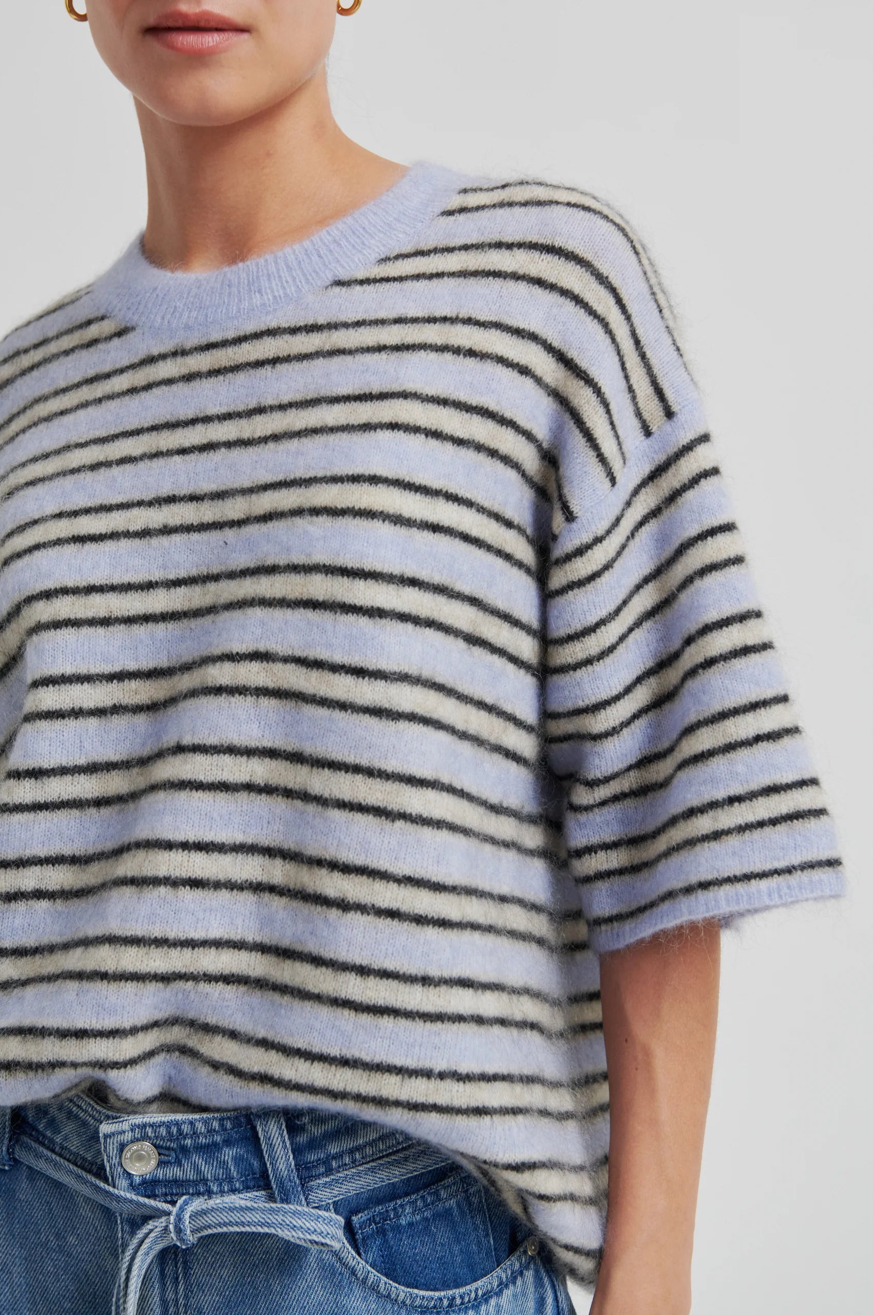 Person wearing a striped sweater and jeans on a plain background from Second Female