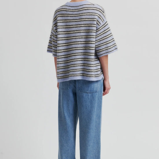 Person wearing a striped sweater and blue jeans on a white background from Second Female