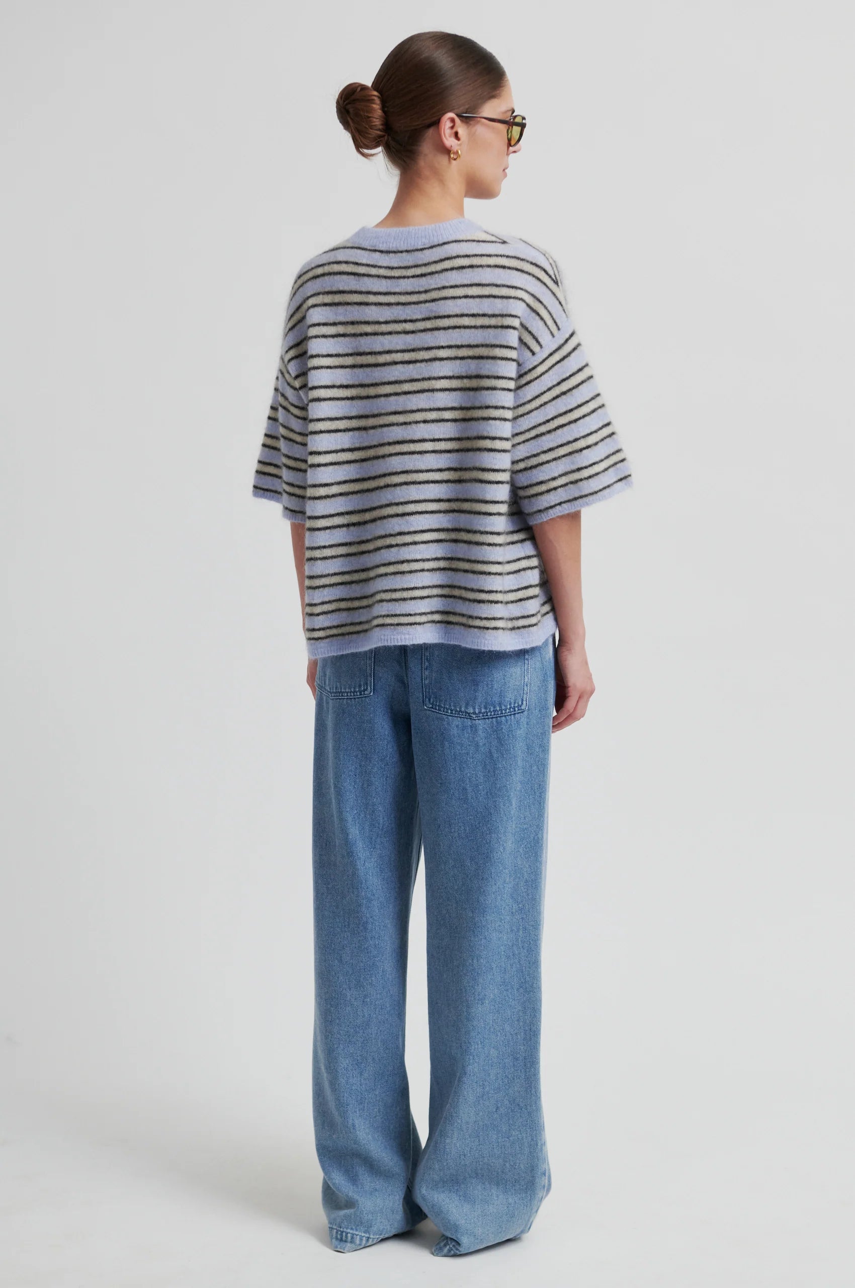 Person wearing a striped sweater and blue jeans on a white background from Second Female