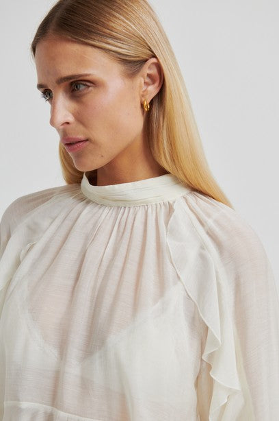 Woman wearing a light-colored blouse with a plain background from second female