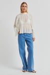 Woman wearing a white blouse and blue jeans on a light gray background from second female